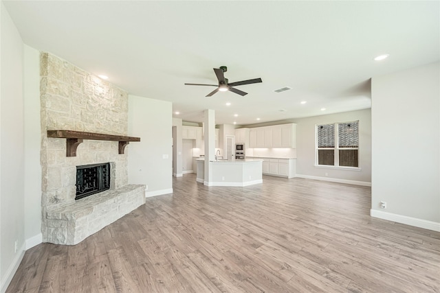 unfurnished living room with ceiling fan, light hardwood / wood-style flooring, and a fireplace