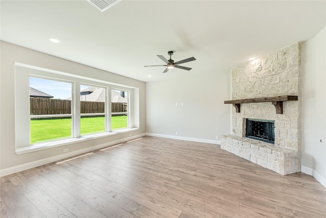 unfurnished living room with ceiling fan, light hardwood / wood-style floors, and a stone fireplace