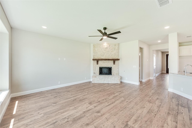 unfurnished living room with a fireplace, light wood-type flooring, and ceiling fan