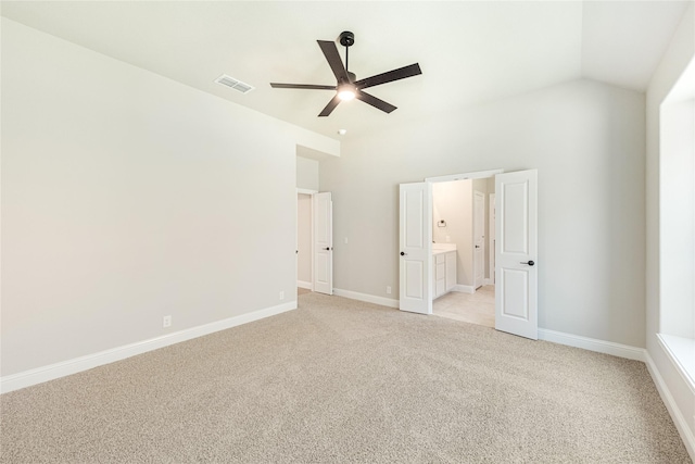 unfurnished bedroom featuring vaulted ceiling, ensuite bathroom, light colored carpet, and ceiling fan