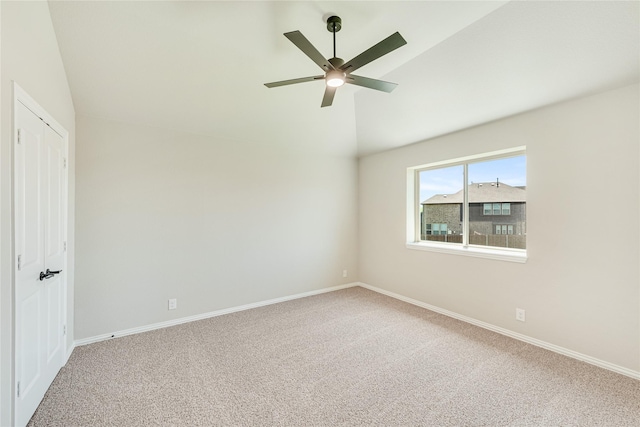 carpeted spare room featuring ceiling fan and vaulted ceiling