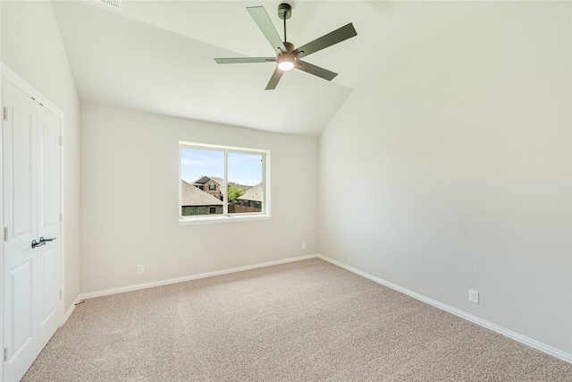 empty room featuring lofted ceiling, carpet flooring, and ceiling fan