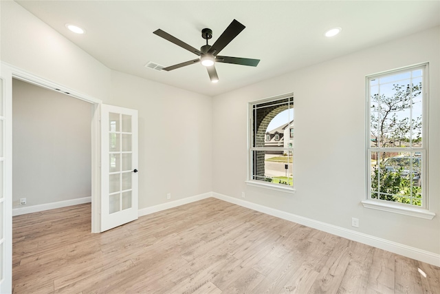 empty room with ceiling fan, light wood-type flooring, and french doors