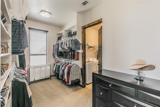 walk in closet featuring separate washer and dryer and light carpet