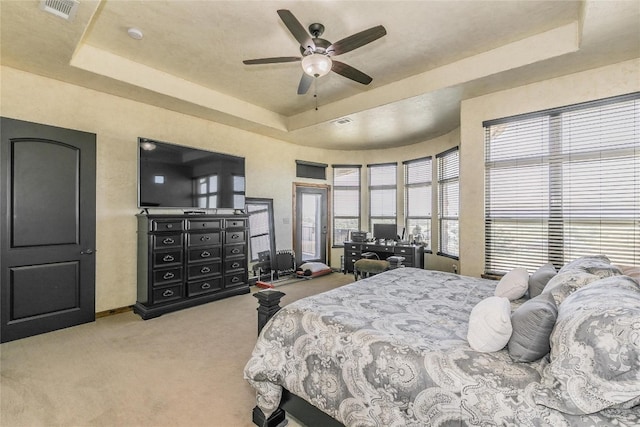 bedroom with a raised ceiling, ceiling fan, and light carpet