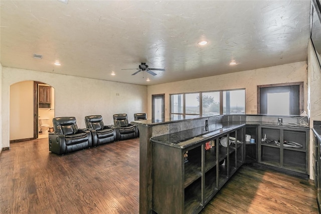 kitchen with dark hardwood / wood-style floors, ceiling fan, dark stone counters, and kitchen peninsula