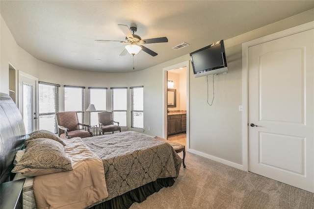 bedroom with light colored carpet, ceiling fan, and ensuite bath