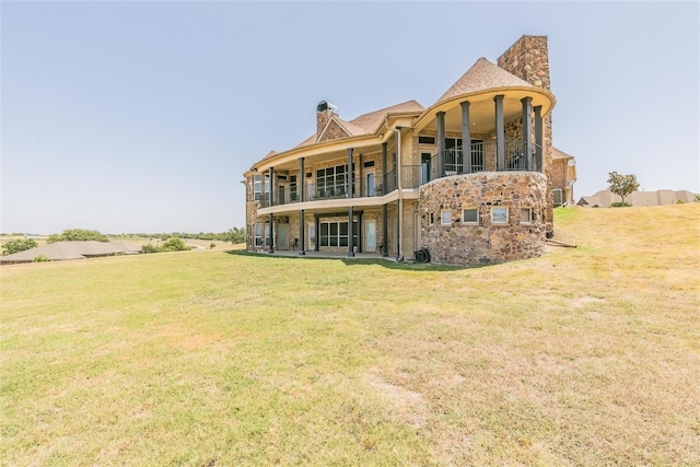 back of house featuring a balcony and a yard