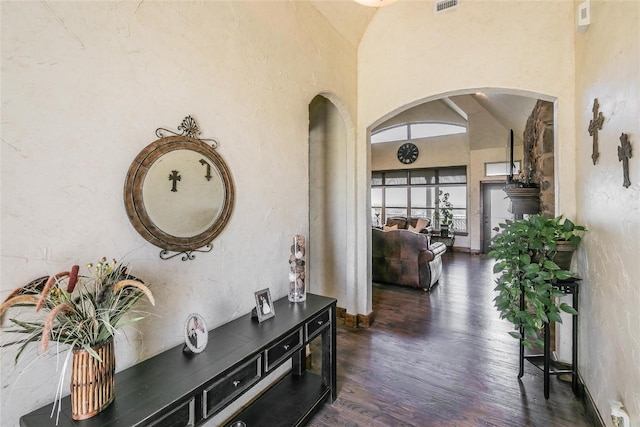 corridor with high vaulted ceiling and dark hardwood / wood-style flooring