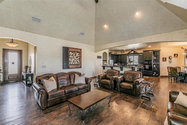 living room with dark hardwood / wood-style flooring and a towering ceiling