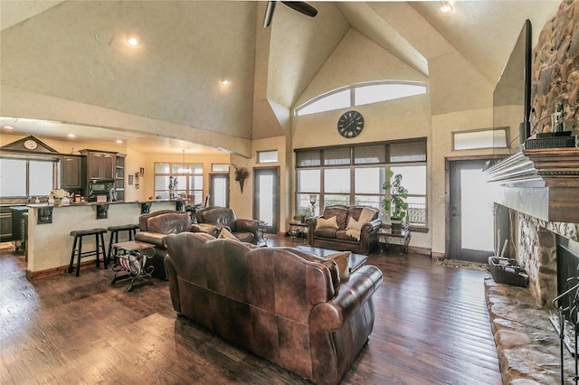 living room with high vaulted ceiling, a fireplace, and dark wood-type flooring