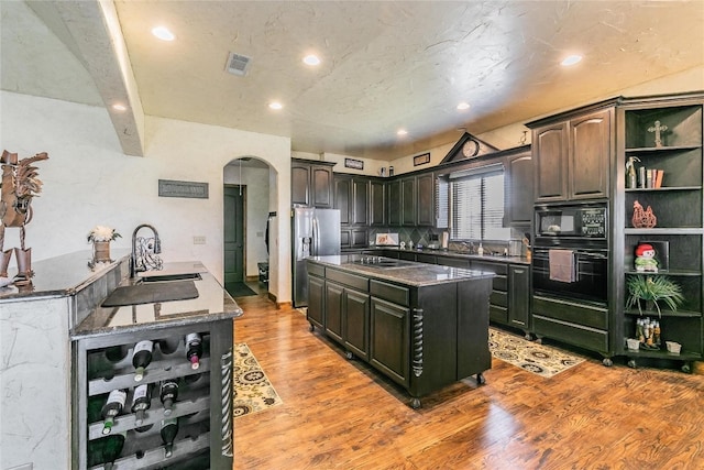 kitchen featuring light hardwood / wood-style flooring, dark brown cabinets, black appliances, and sink