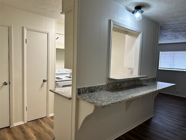 kitchen with a textured ceiling, white gas stove, dark wood-type flooring, and light stone countertops