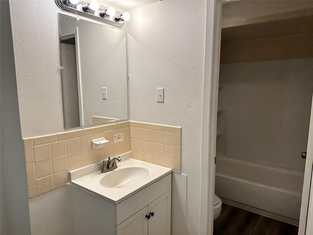 full bathroom with large vanity, shower / bathtub combination, toilet, tasteful backsplash, and hardwood / wood-style floors