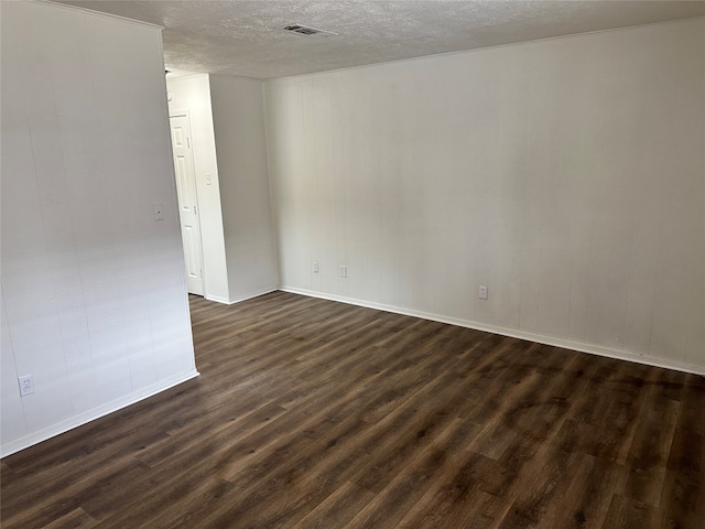 empty room with dark hardwood / wood-style flooring and a textured ceiling