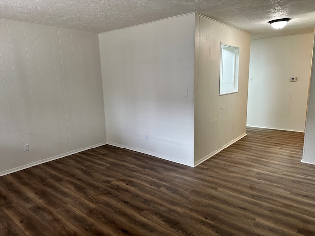 unfurnished room with dark hardwood / wood-style flooring and a textured ceiling