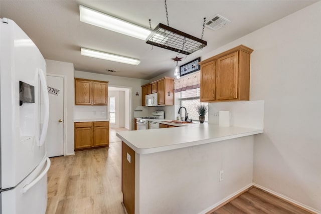 kitchen featuring light countertops, visible vents, a sink, light wood-type flooring, and white appliances