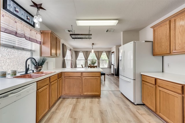 kitchen featuring white appliances, visible vents, a peninsula, light countertops, and a sink