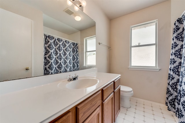 bathroom featuring plenty of natural light, toilet, tile floors, and large vanity