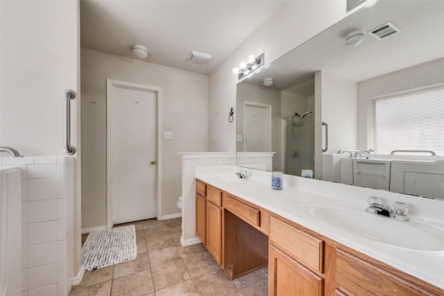 bathroom featuring a sink, double vanity, a stall shower, and washing machine and dryer