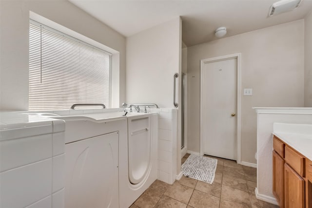 clothes washing area featuring light tile patterned floors, washer / clothes dryer, and baseboards