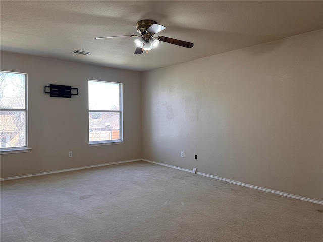 spare room with ceiling fan, a textured ceiling, visible vents, baseboards, and carpet