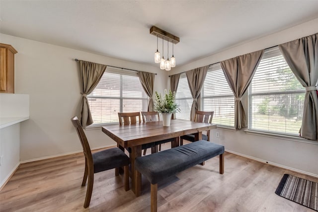 dining area featuring a wealth of natural light, baseboards, light wood finished floors, and an inviting chandelier