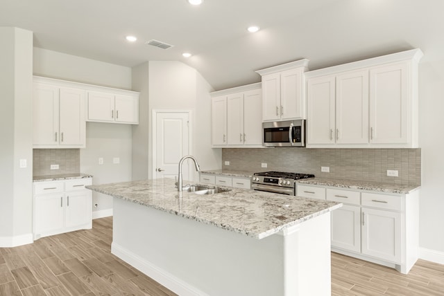 kitchen with stainless steel appliances, white cabinetry, sink, an island with sink, and decorative backsplash