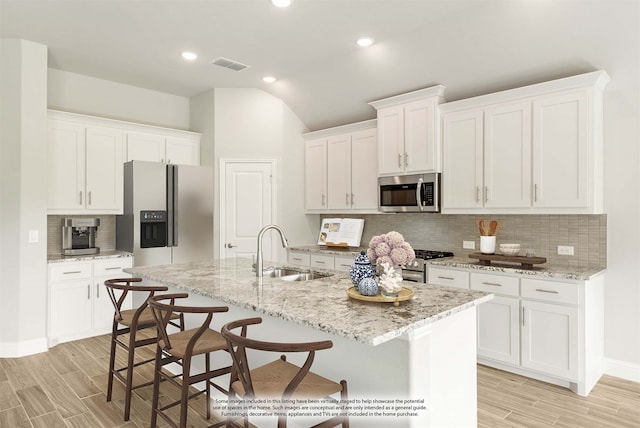 kitchen featuring decorative backsplash, stainless steel appliances, sink, and a center island with sink