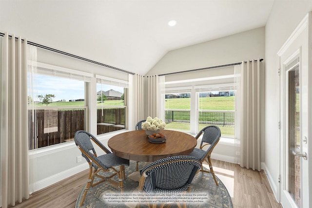 dining room featuring lofted ceiling and light hardwood / wood-style flooring