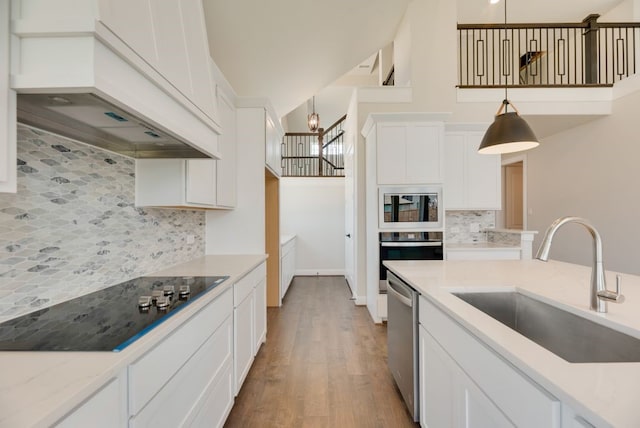 kitchen featuring appliances with stainless steel finishes, tasteful backsplash, sink, white cabinetry, and hanging light fixtures