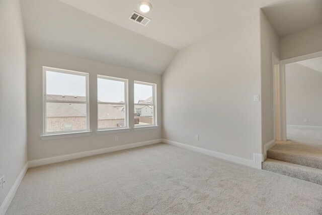 empty room with light carpet and lofted ceiling