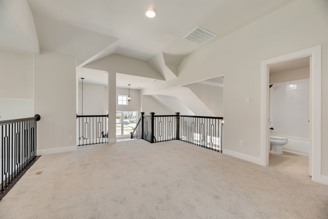 unfurnished room with visible vents, baseboards, lofted ceiling, and carpet