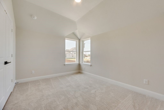 interior space featuring light colored carpet, baseboards, and lofted ceiling