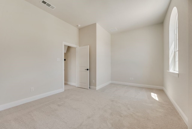 unfurnished room with light carpet, visible vents, and baseboards