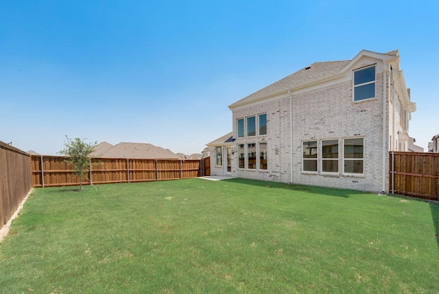 rear view of property with a yard, a fenced backyard, and brick siding