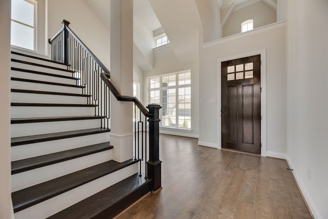 entrance foyer with a wealth of natural light, a towering ceiling, and wood finished floors