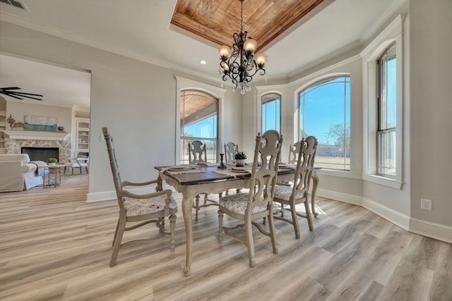 dining space with a fireplace, a tray ceiling, light hardwood / wood-style floors, and plenty of natural light