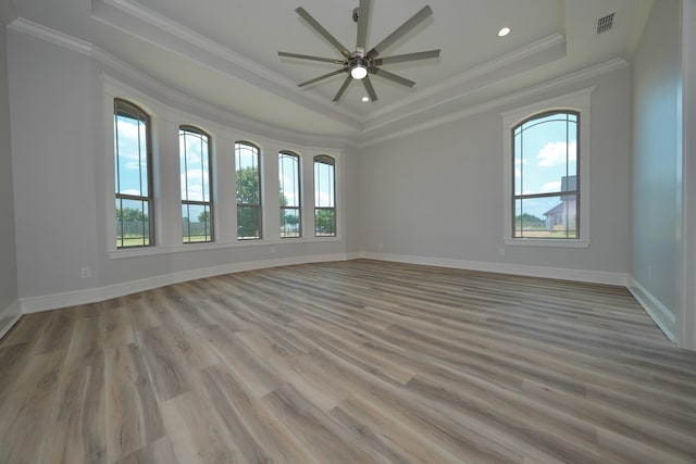 empty room featuring a wealth of natural light, ornamental molding, light hardwood / wood-style flooring, and ceiling fan