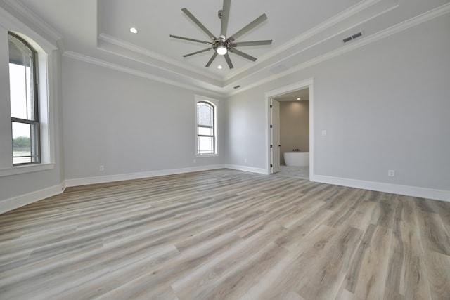 spare room featuring crown molding, light hardwood / wood-style flooring, a tray ceiling, and ceiling fan