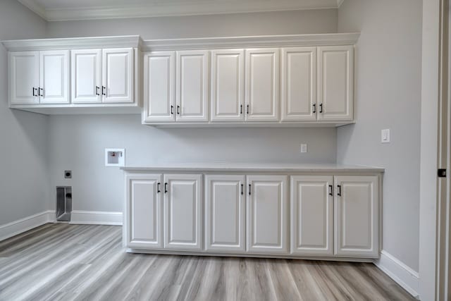 washroom featuring ornamental molding, hookup for a washing machine, light hardwood / wood-style floors, and cabinets