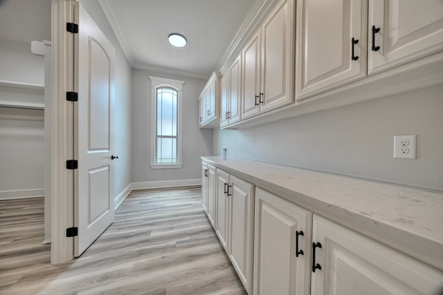 laundry room with crown molding, washer hookup, light hardwood / wood-style floors, and cabinets