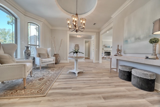 living area featuring light hardwood / wood-style floors, crown molding, and an inviting chandelier