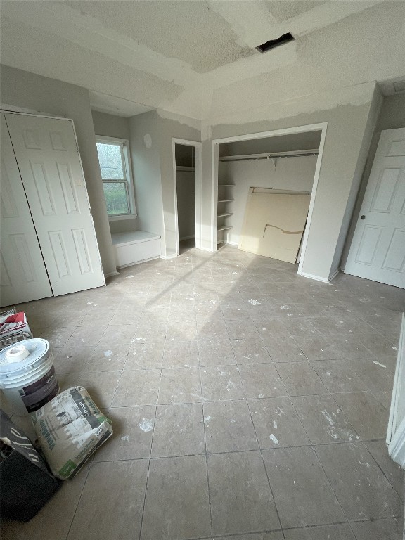 unfurnished bedroom with light tile floors and a textured ceiling