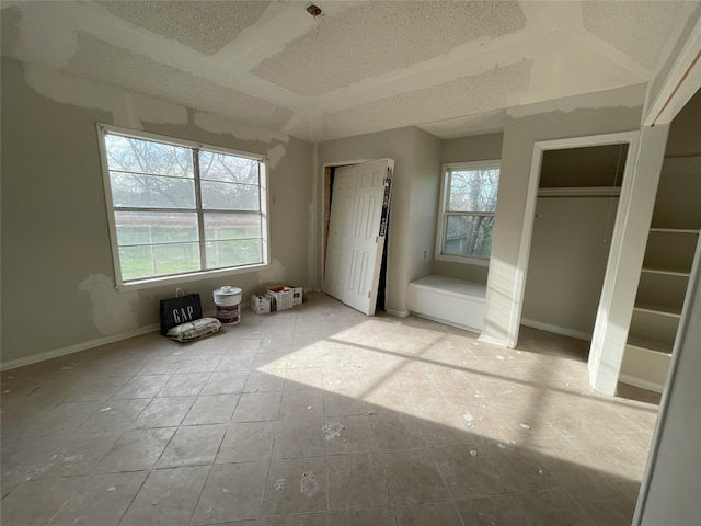 unfurnished bedroom with two closets, a textured ceiling, and light tile flooring