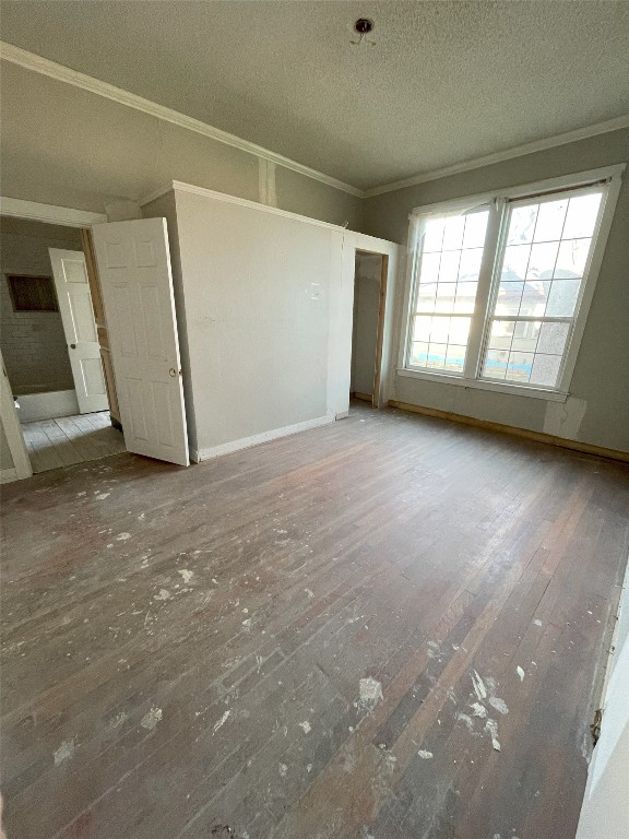 empty room with ornamental molding, light hardwood / wood-style flooring, and a textured ceiling