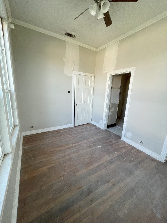 unfurnished bedroom featuring ceiling fan, dark wood-type flooring, a textured ceiling, and ornamental molding