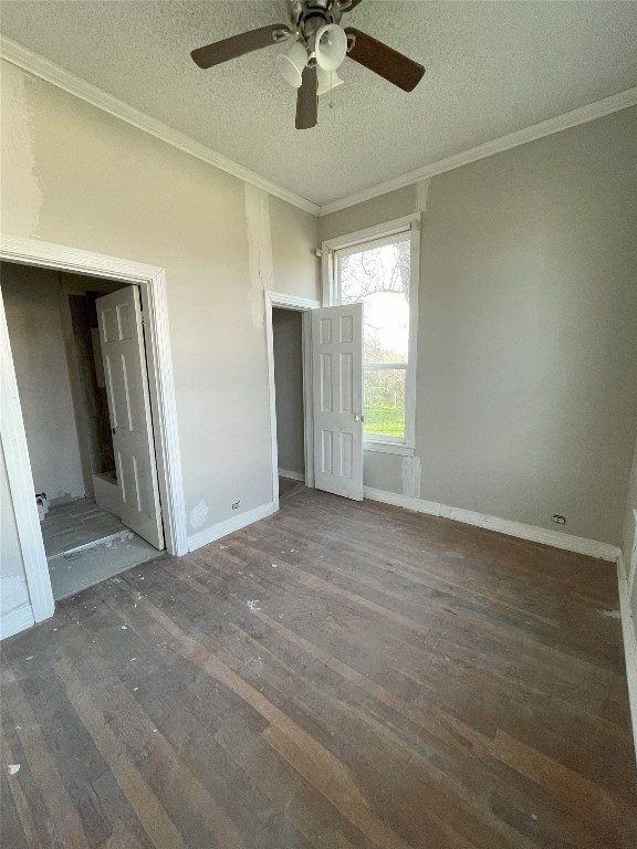 interior space featuring ceiling fan, dark hardwood / wood-style flooring, a textured ceiling, and ornamental molding