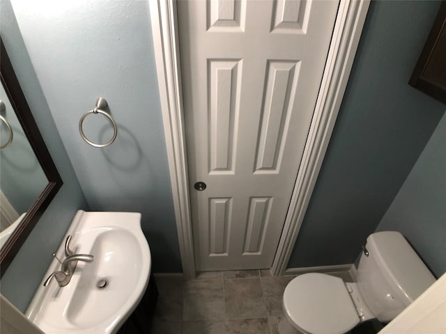 bathroom featuring toilet, tile flooring, and sink