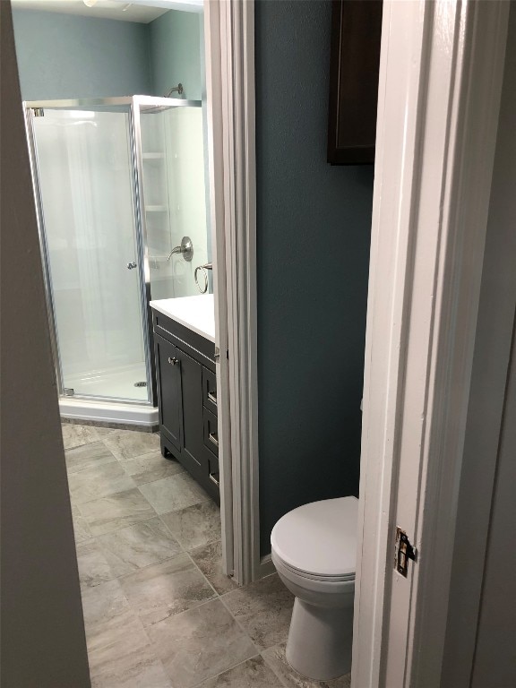 bathroom with walk in shower, vanity, tile floors, and toilet